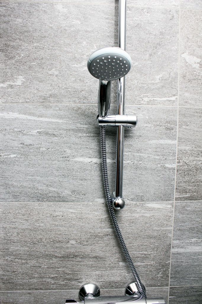 A close up of a shower head and hose in a bathroom.