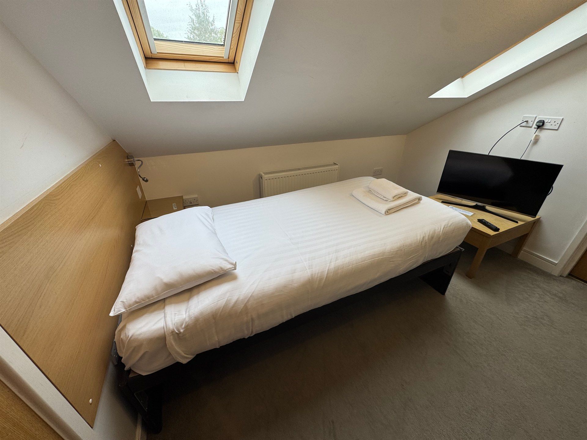A bedroom with a single bed and a flat screen tv