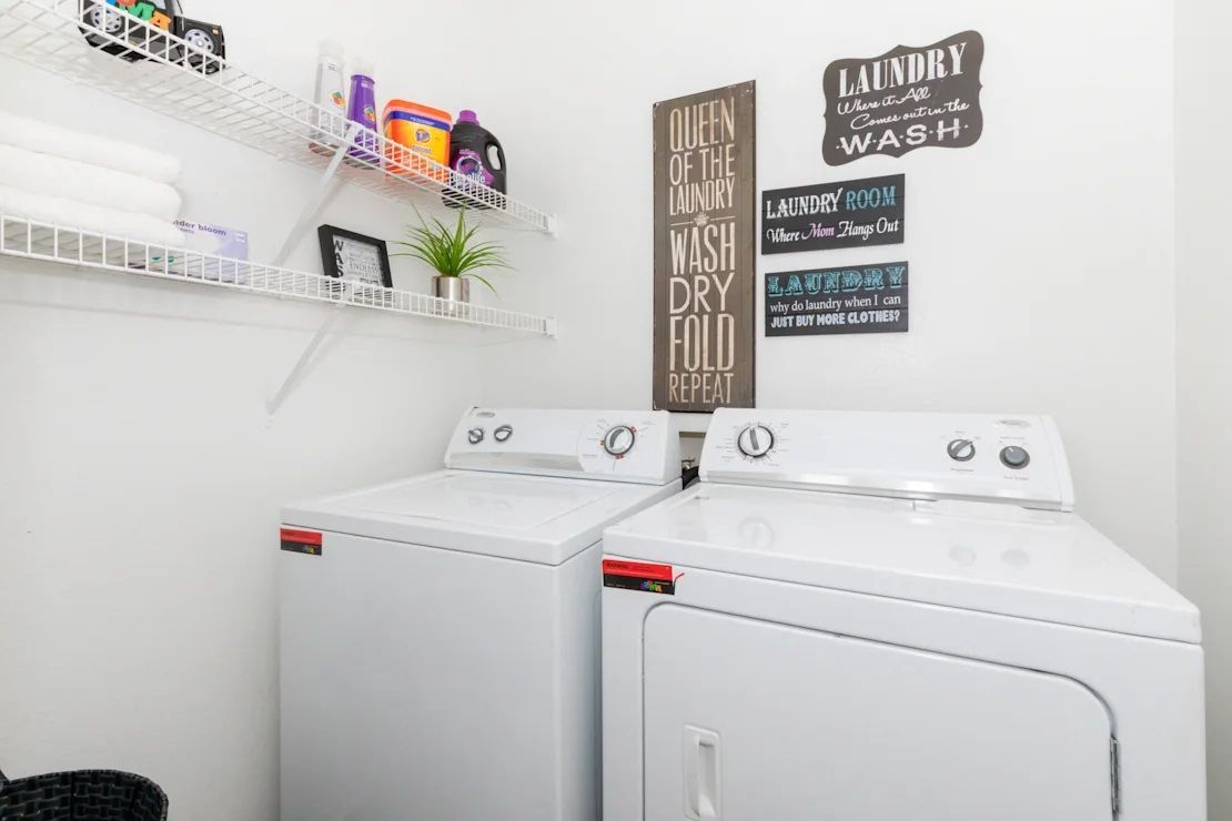 A laundry room with a washer and dryer and a sign on the wall.