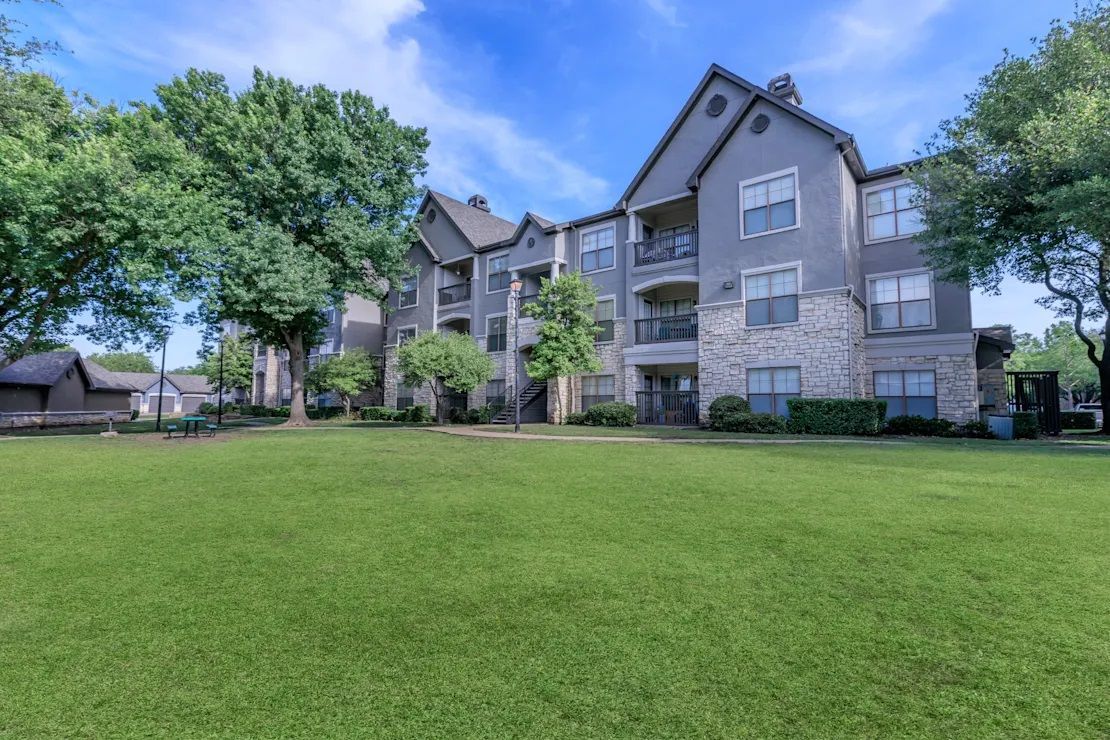 A large apartment building with a large lawn in front of it.