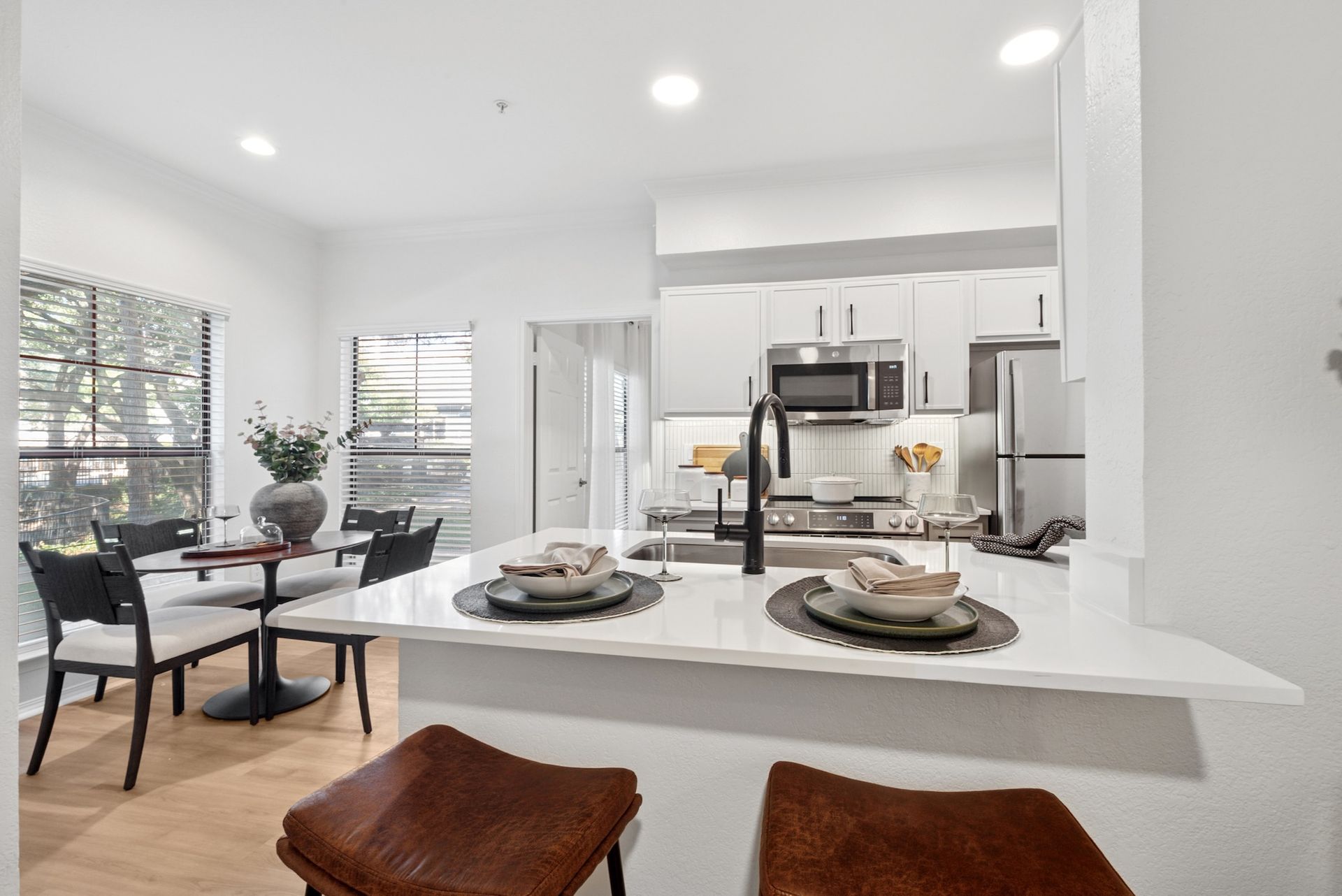 Modern kitchen with breakfast bar, dining area, and stainless steel appliances.