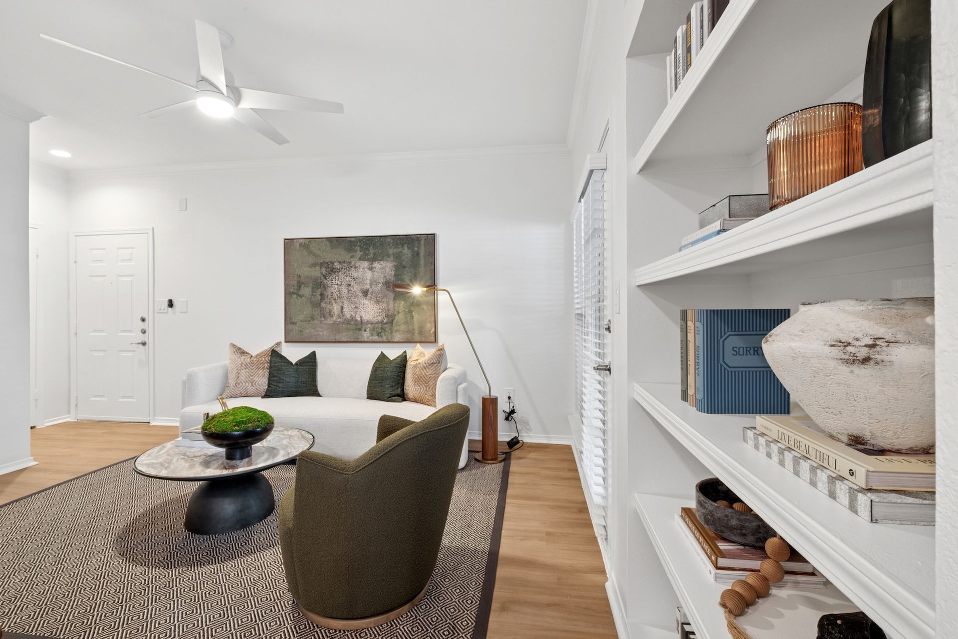Living room with white walls, built-in shelves, sofa, chair, and coffee table.