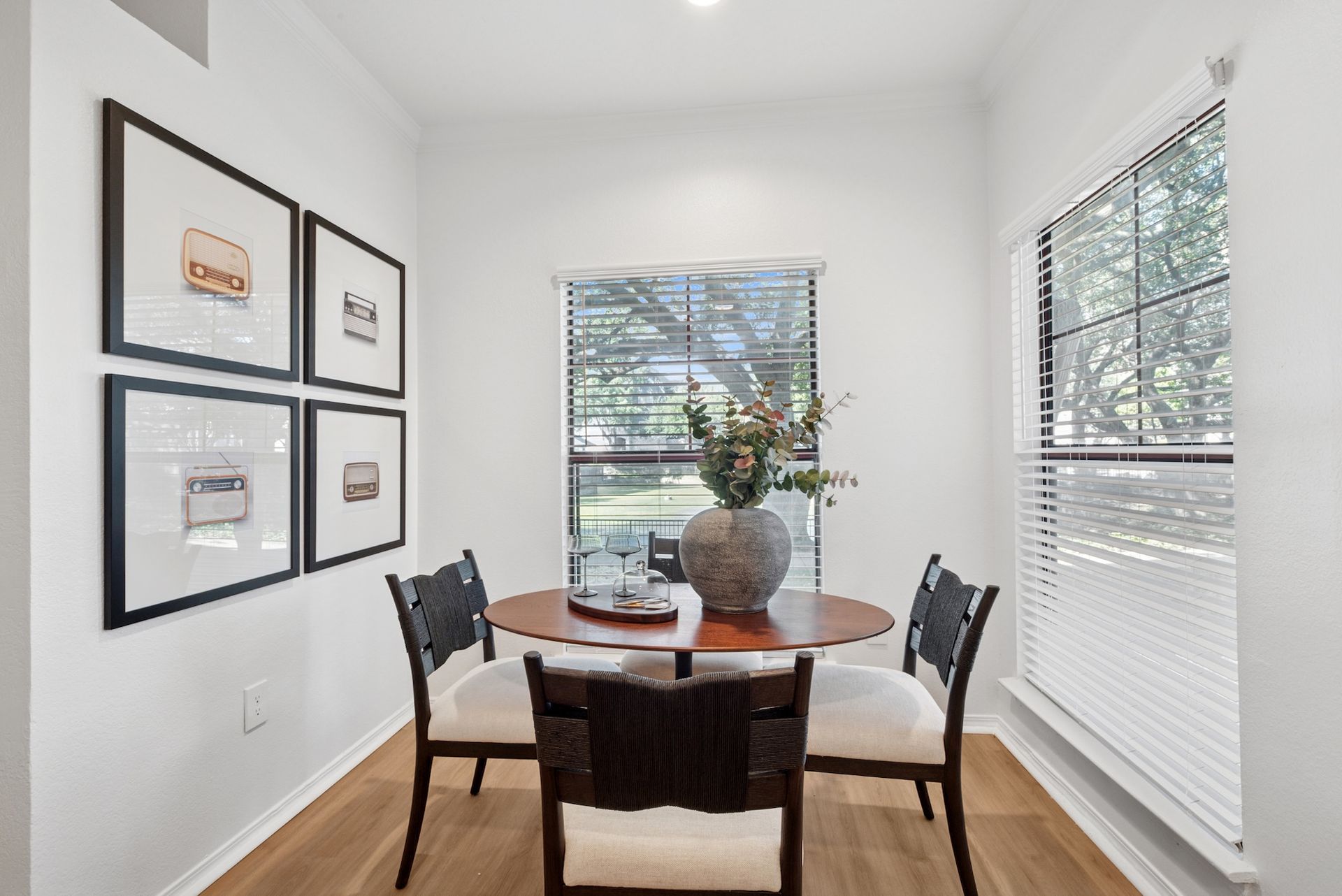 Dining nook with table, chairs, art, and windows.