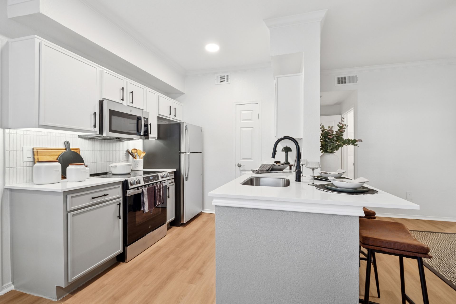 Modern kitchen with white cabinets, stainless steel appliances, and island with black faucet.