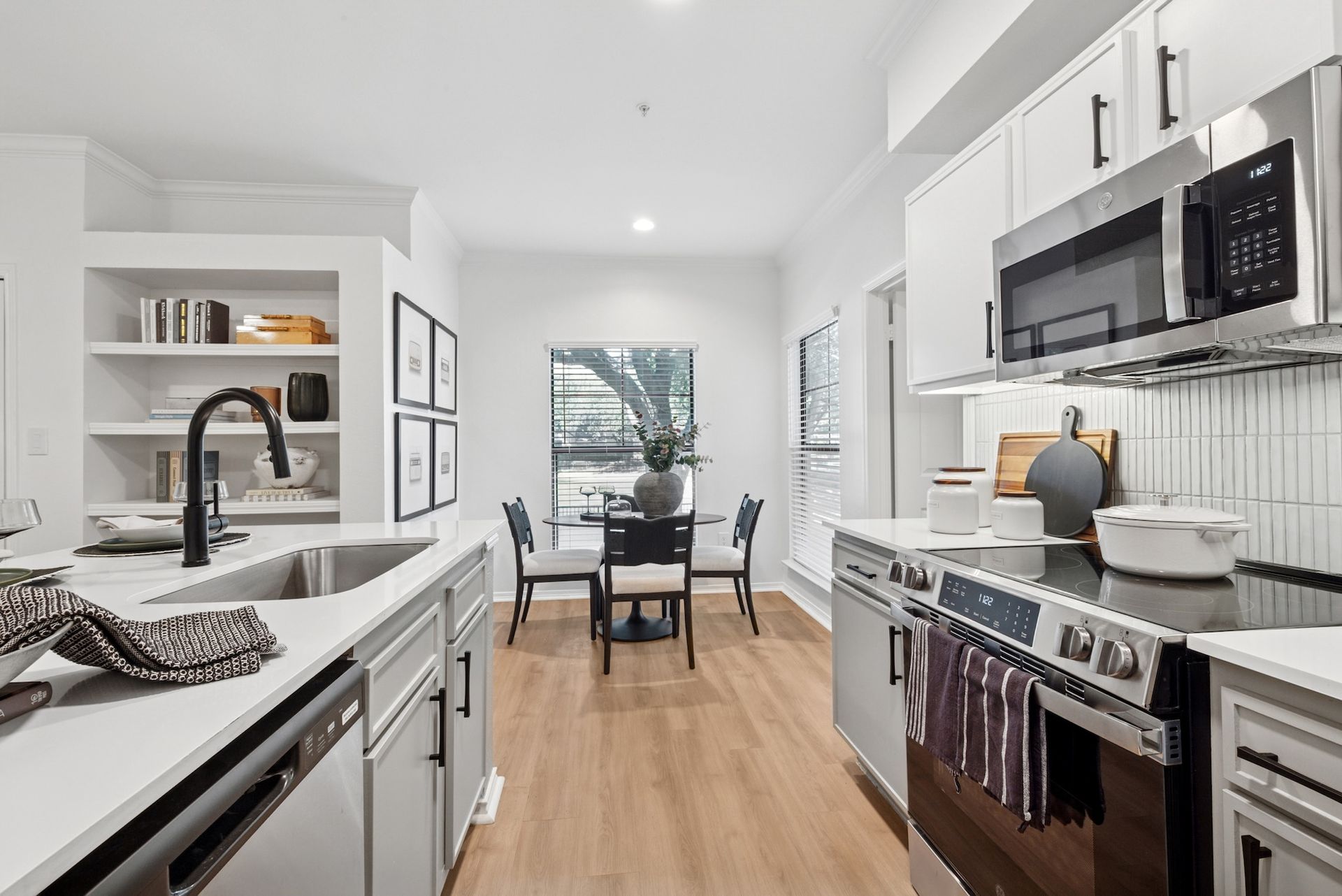 Modern kitchen with white cabinets, stainless steel appliances, and a dining area.