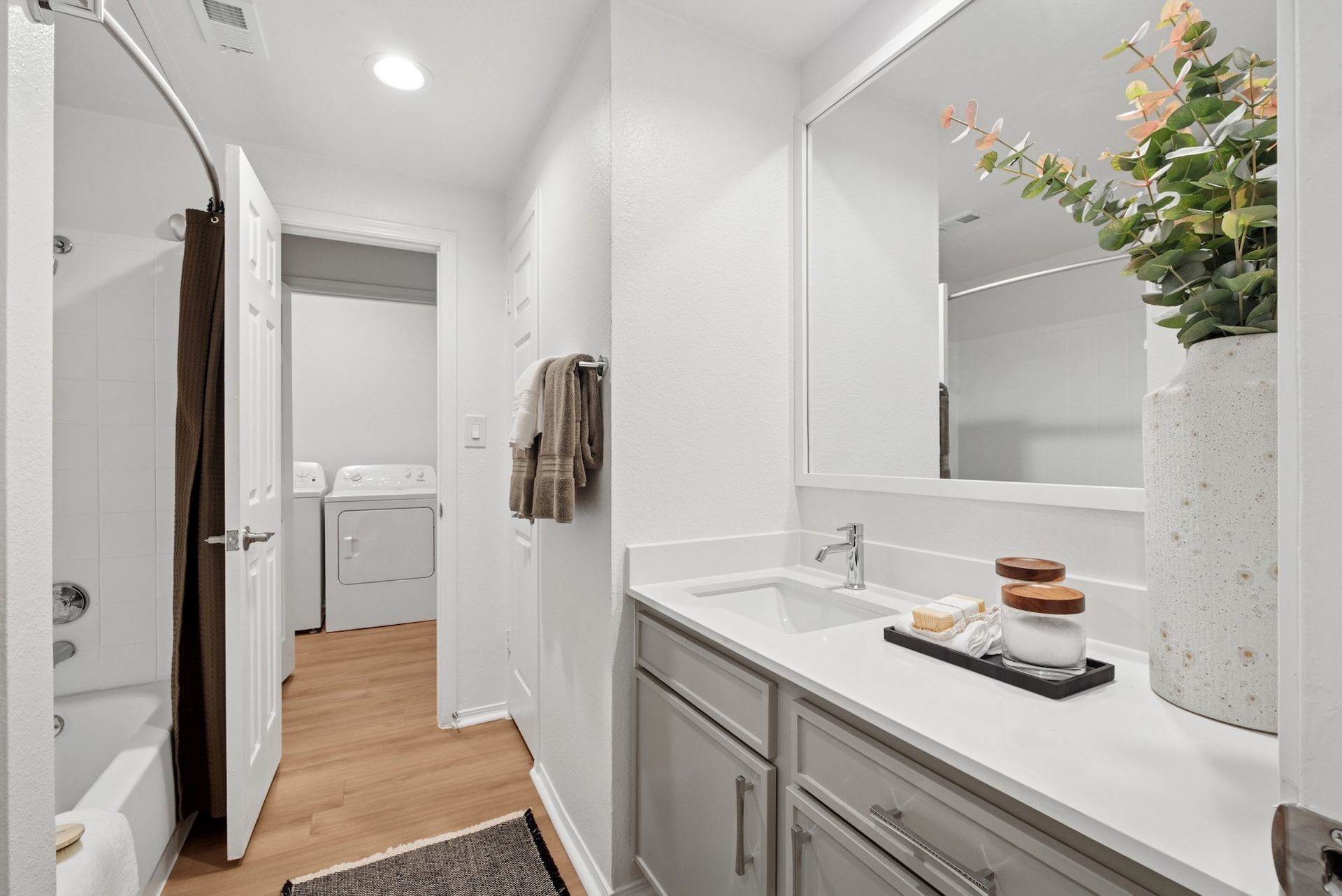 Bathroom with gray vanity, white countertop, and doorway to laundry area.