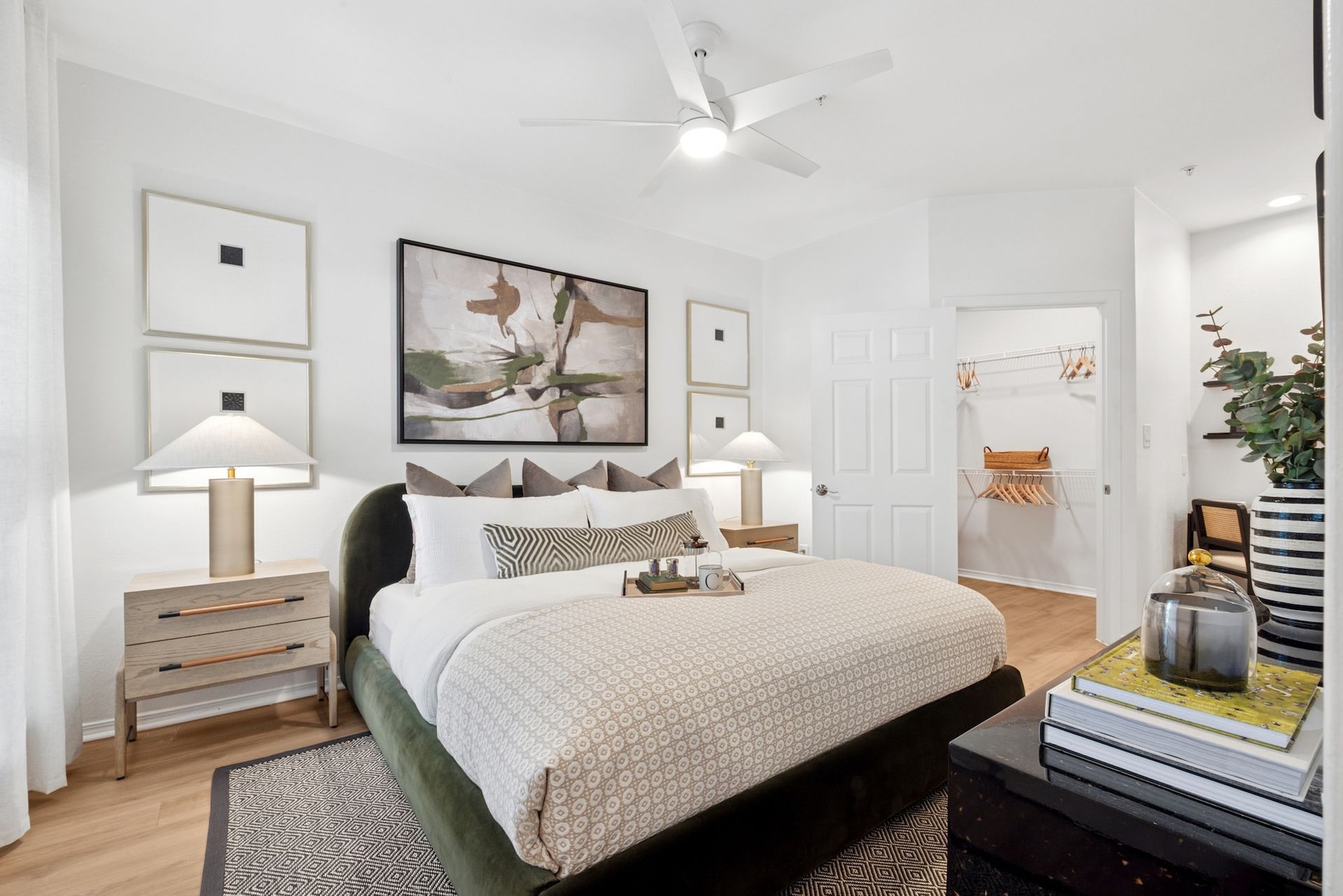 Bedroom with bed, art, and furniture, featuring light colors and a modern design.