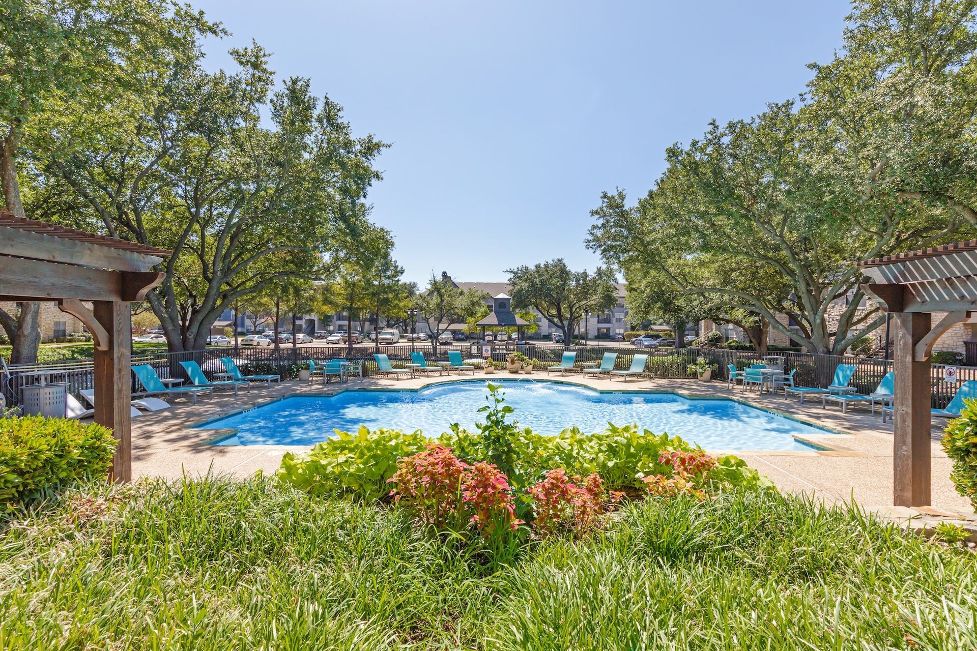 A large swimming pool surrounded by trees and chairs in a park.