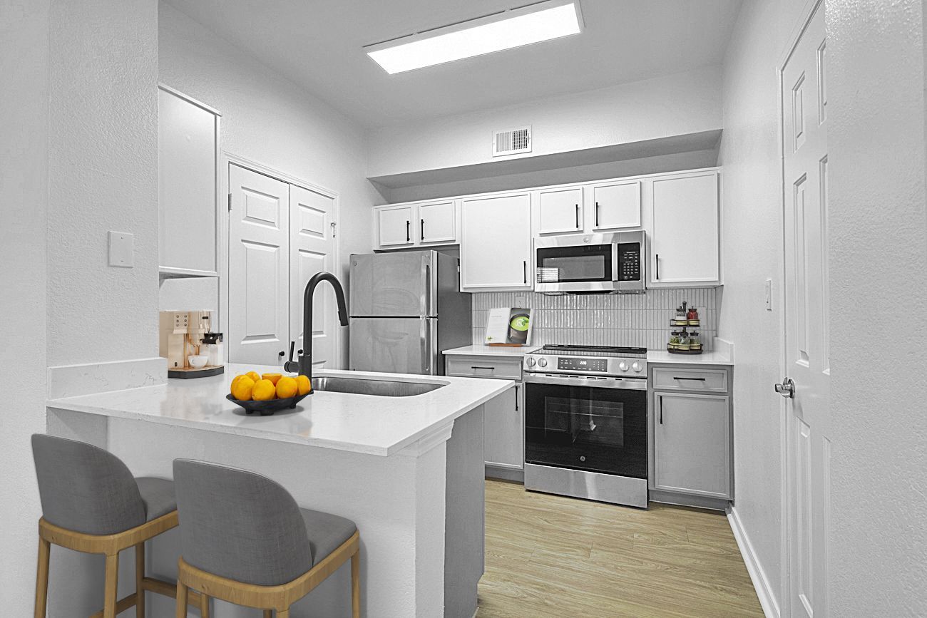 Modern white kitchen with stainless steel appliances, island with seating.