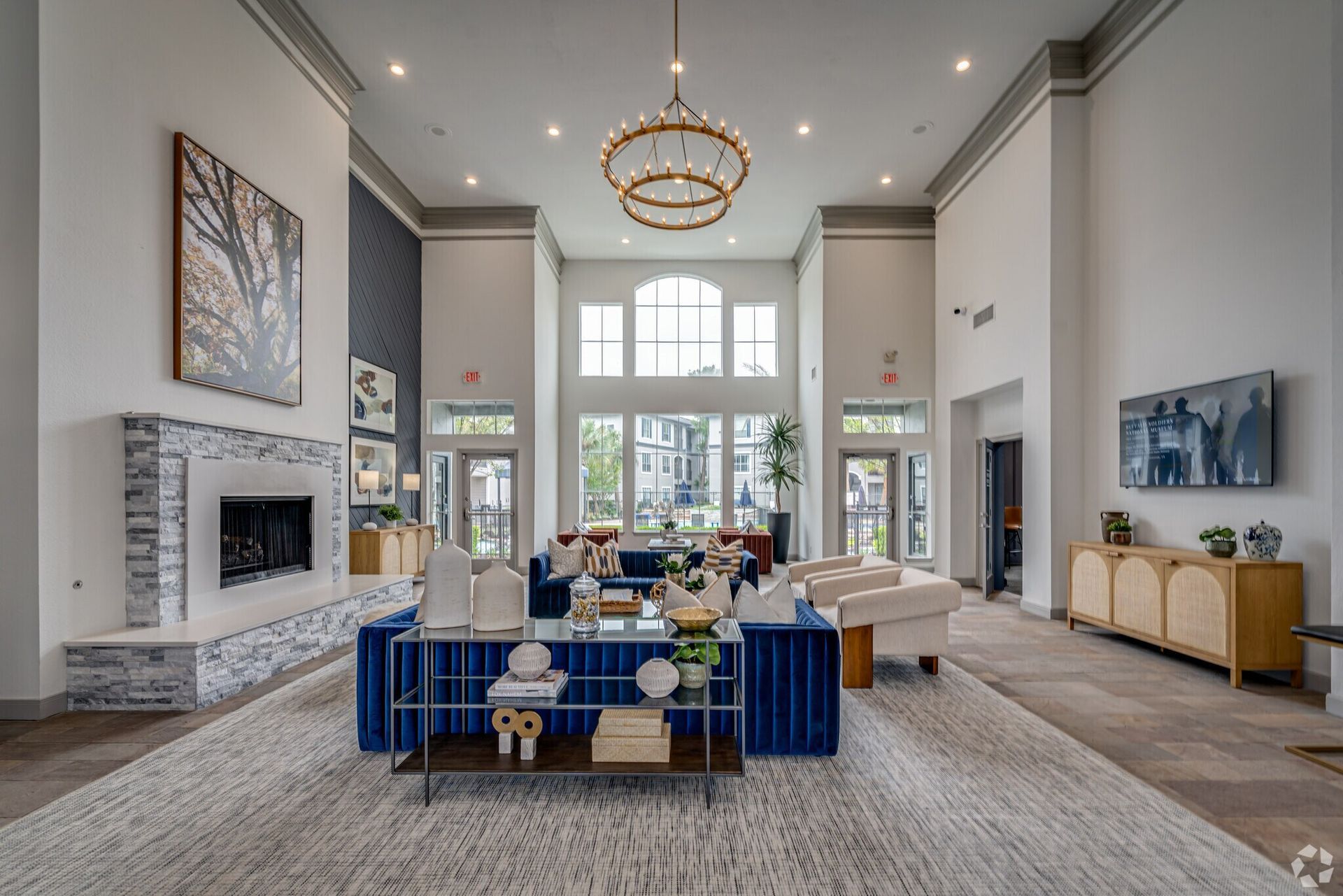 Lobby with blue velvet sofa, fireplace, chandelier, large windows.  Neutral colors.