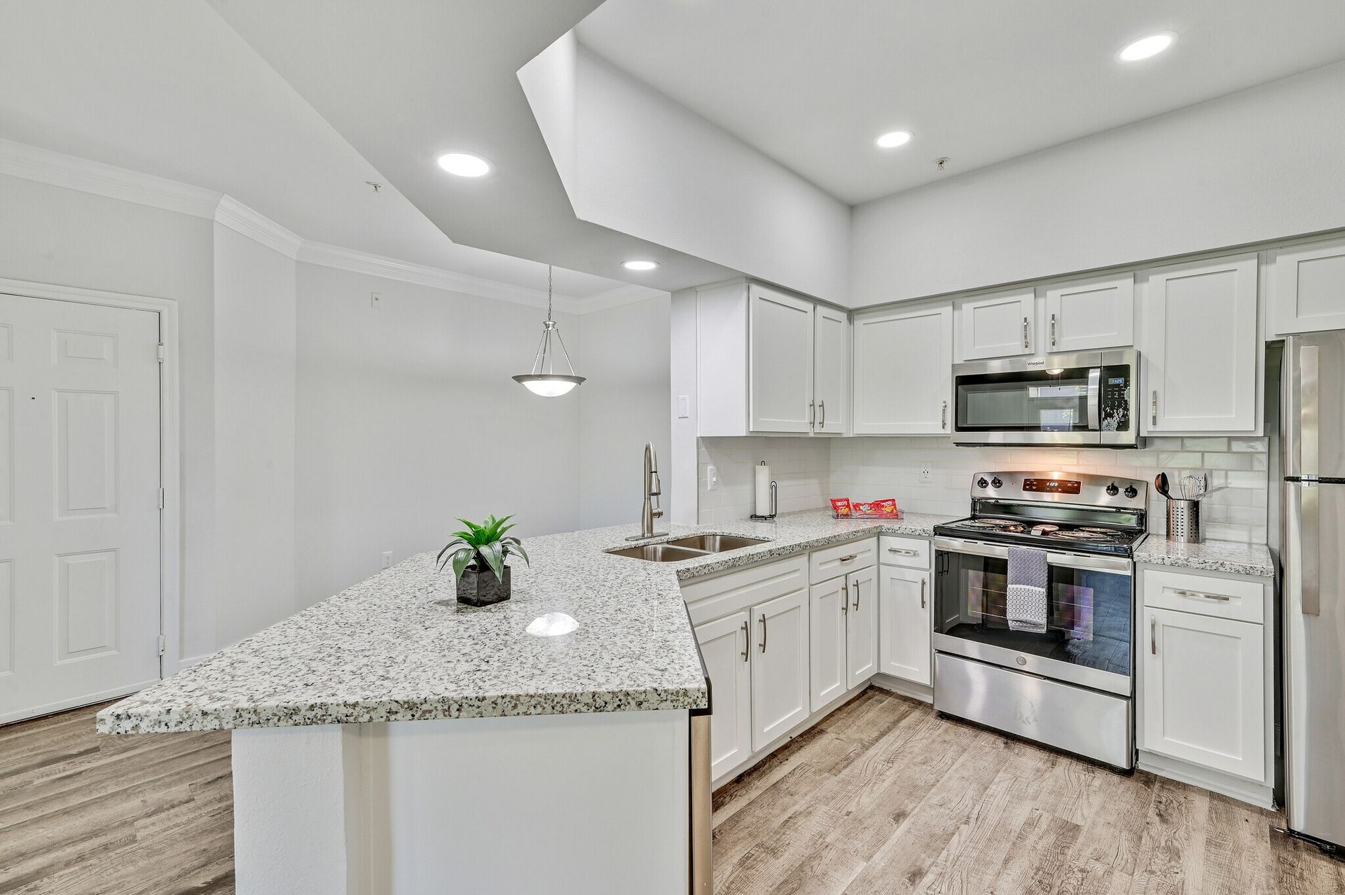 Bright, modern kitchen with white cabinets, granite countertops, and stainless steel appliances.