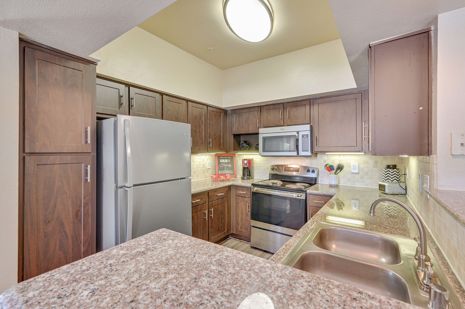 Kitchen with brown cabinets, stainless steel appliances, and granite countertops.
