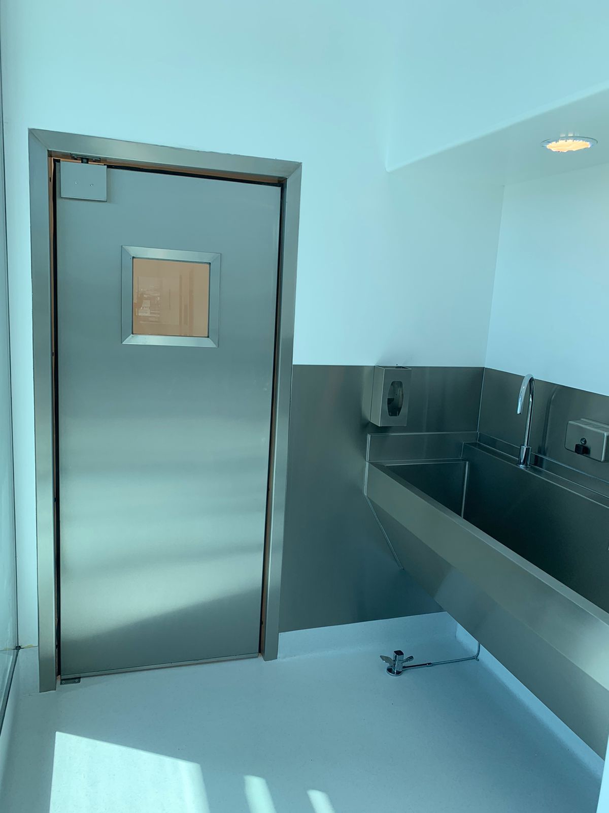 Una habitación con lavabo y puerta de acero inoxidable.