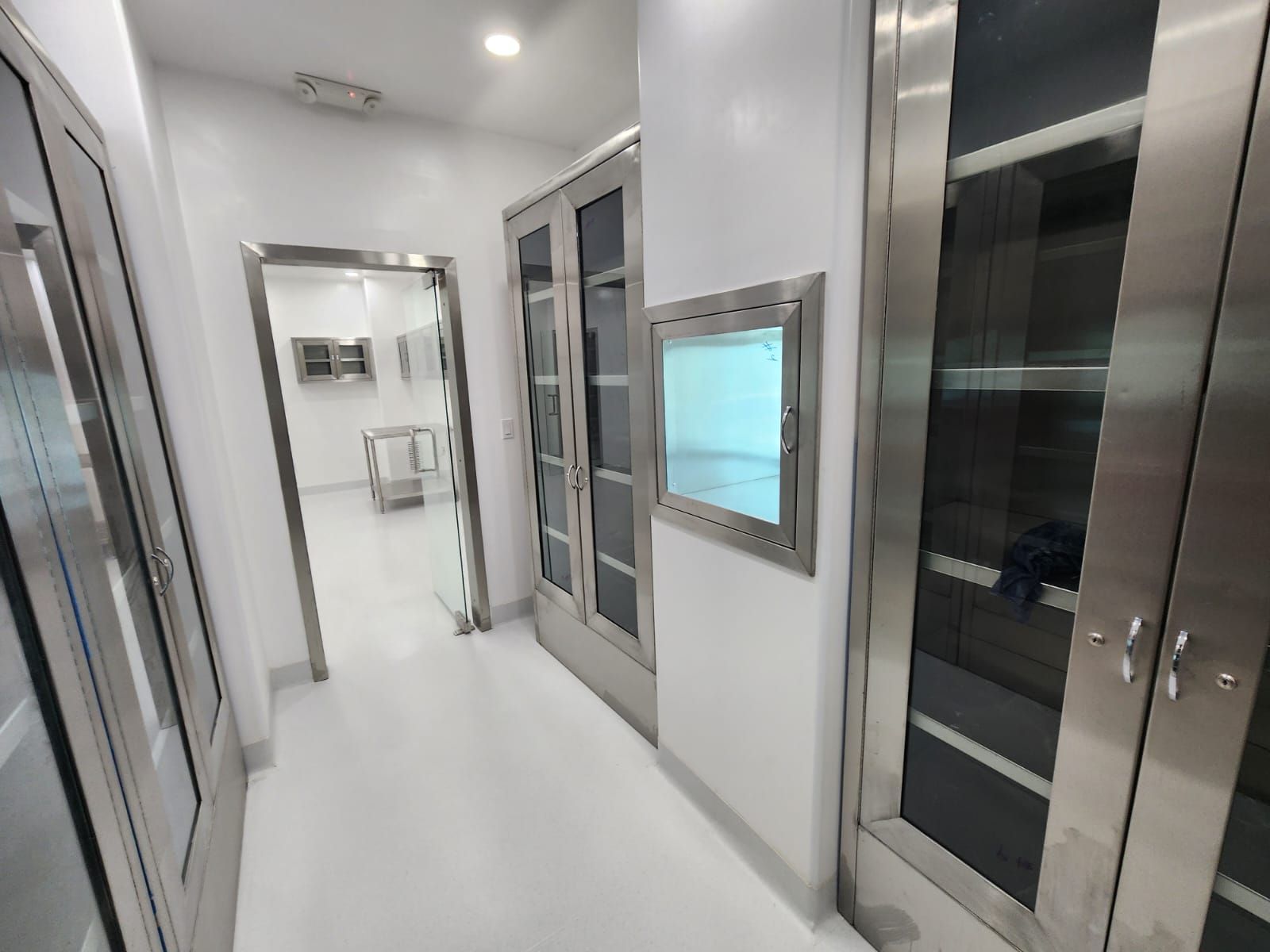 Un pasillo con puertas de acero inoxidable y una ventana en la pared.
