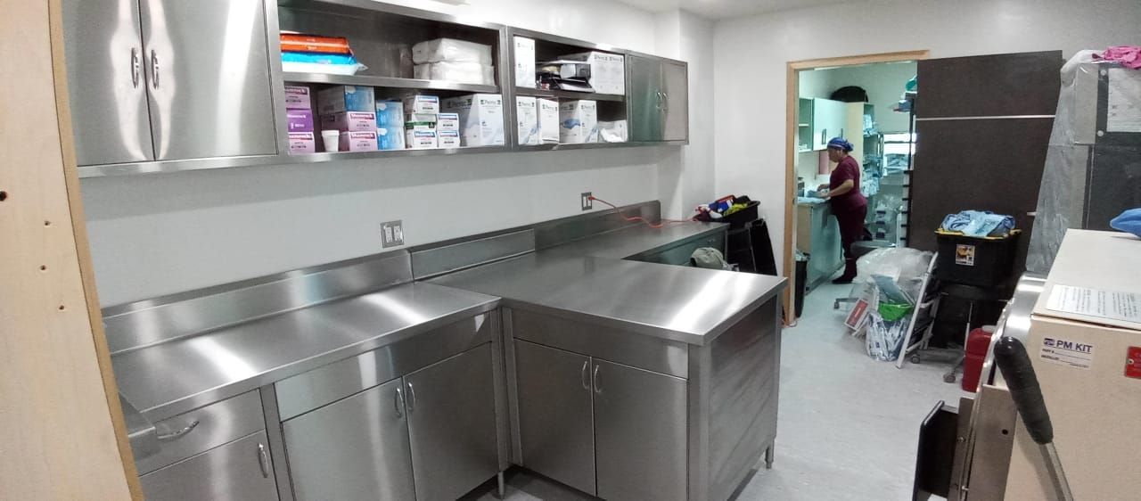 Un cuarto de lavado con electrodomésticos de acero inoxidable y un hombre de pie al fondo.