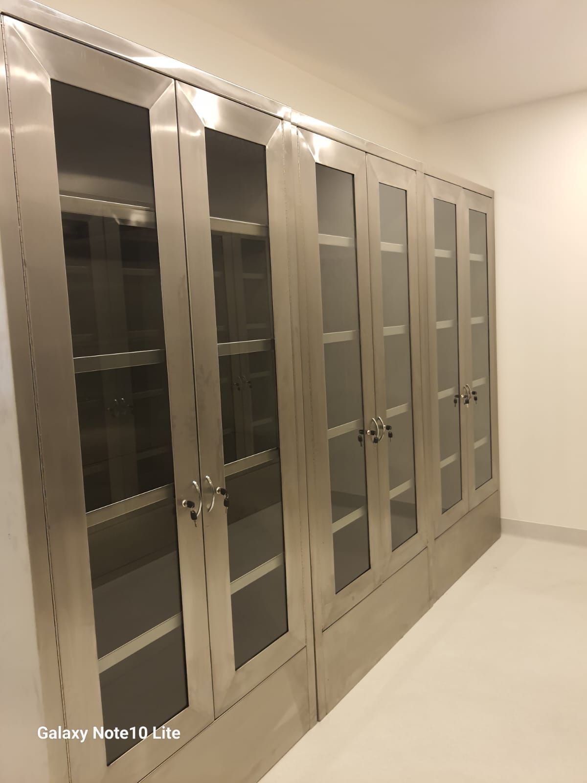 Una fila de armarios de acero inoxidable con puertas de cristal en una habitación.