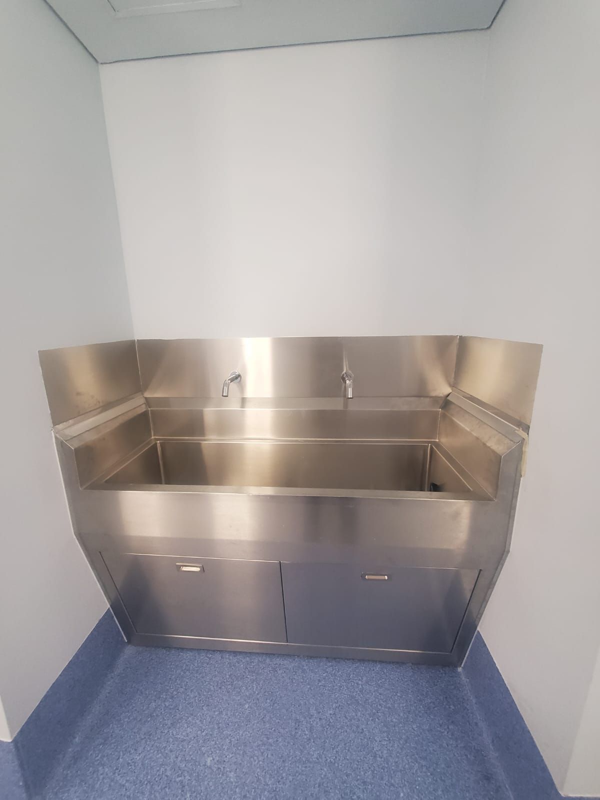 Un fregadero de acero inoxidable en una habitación con suelo azul.