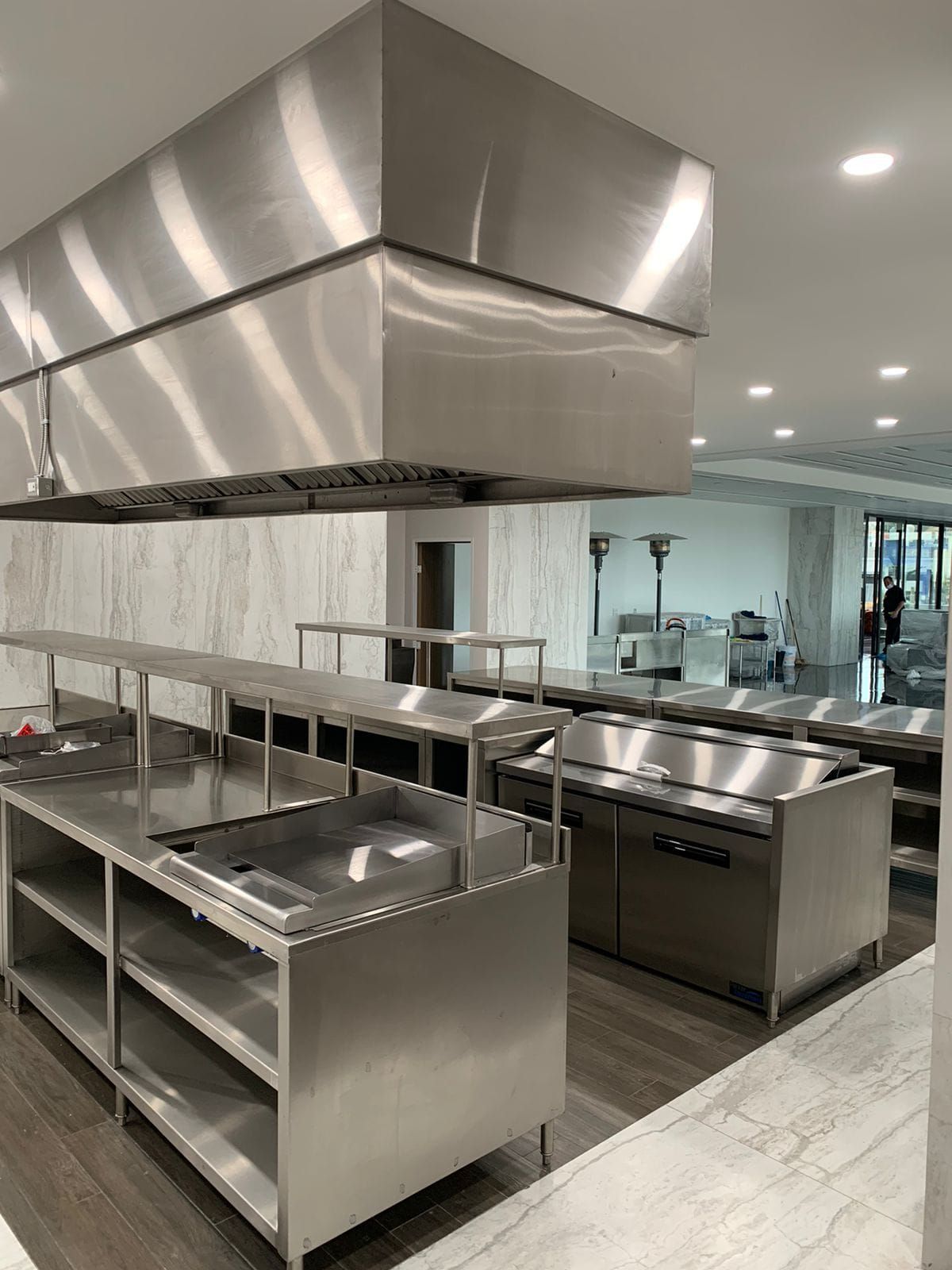 Una amplia cocina con electrodomésticos y estantes de acero inoxidable.