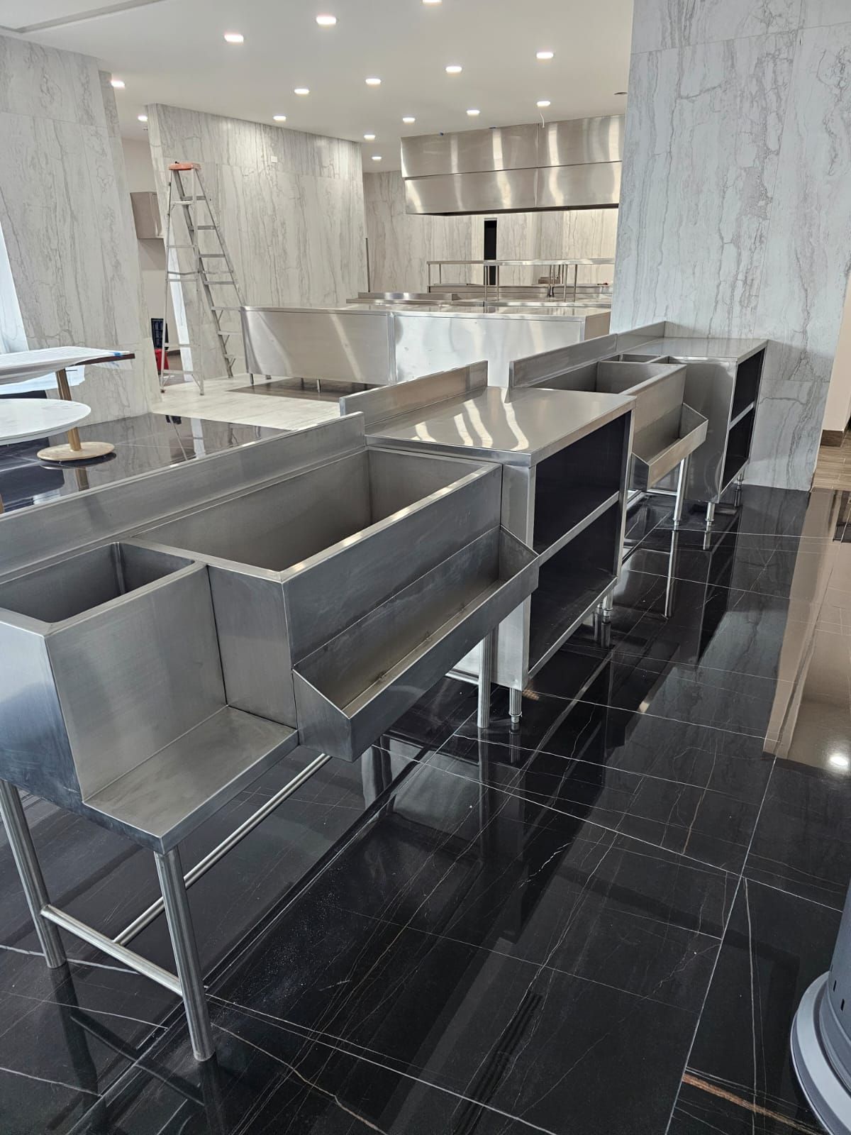 Una sala llena de fregaderos y mesas de acero inoxidable.