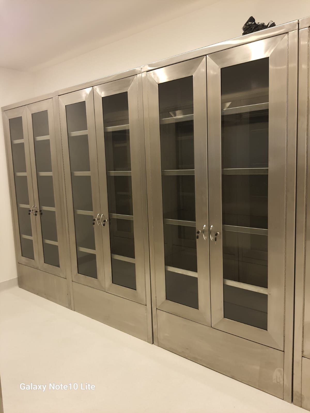 Una fila de armarios de acero inoxidable con puertas de cristal en una habitación.