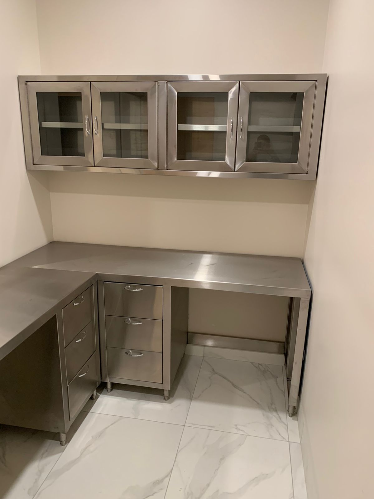 Un escritorio de acero inoxidable con cajones y armarios en una habitación.