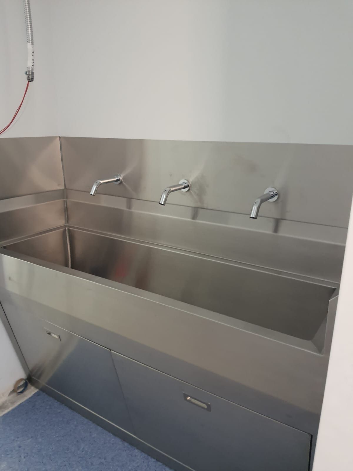 Un fregadero de acero inoxidable con tres grifos en una habitación.