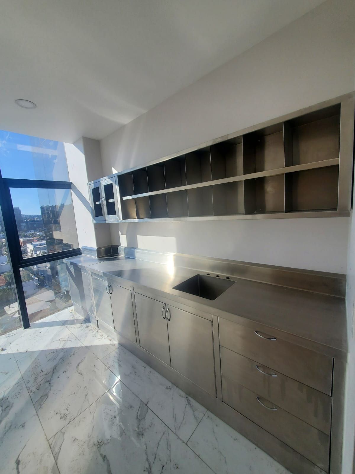 Una cocina con gabinetes de acero inoxidable y fregadero.