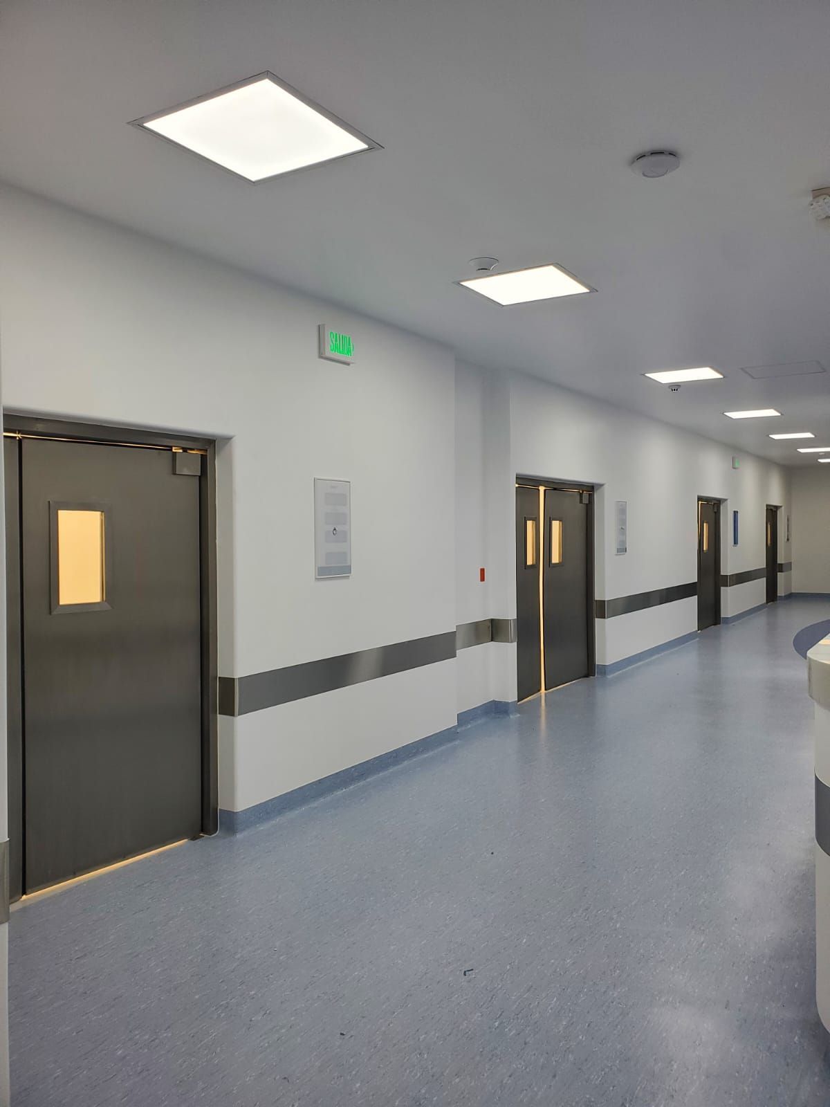 Un largo pasillo en un hospital con puertas de acero inoxidable