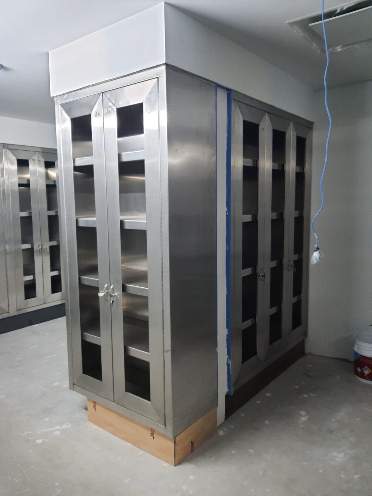 Un gran armario de acero inoxidable con puertas y estantes de cristal.