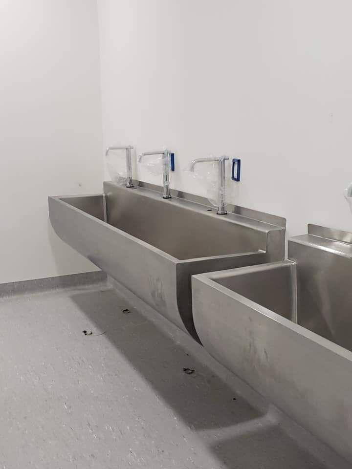 Una fila de lavabos de acero inoxidable en un baño.