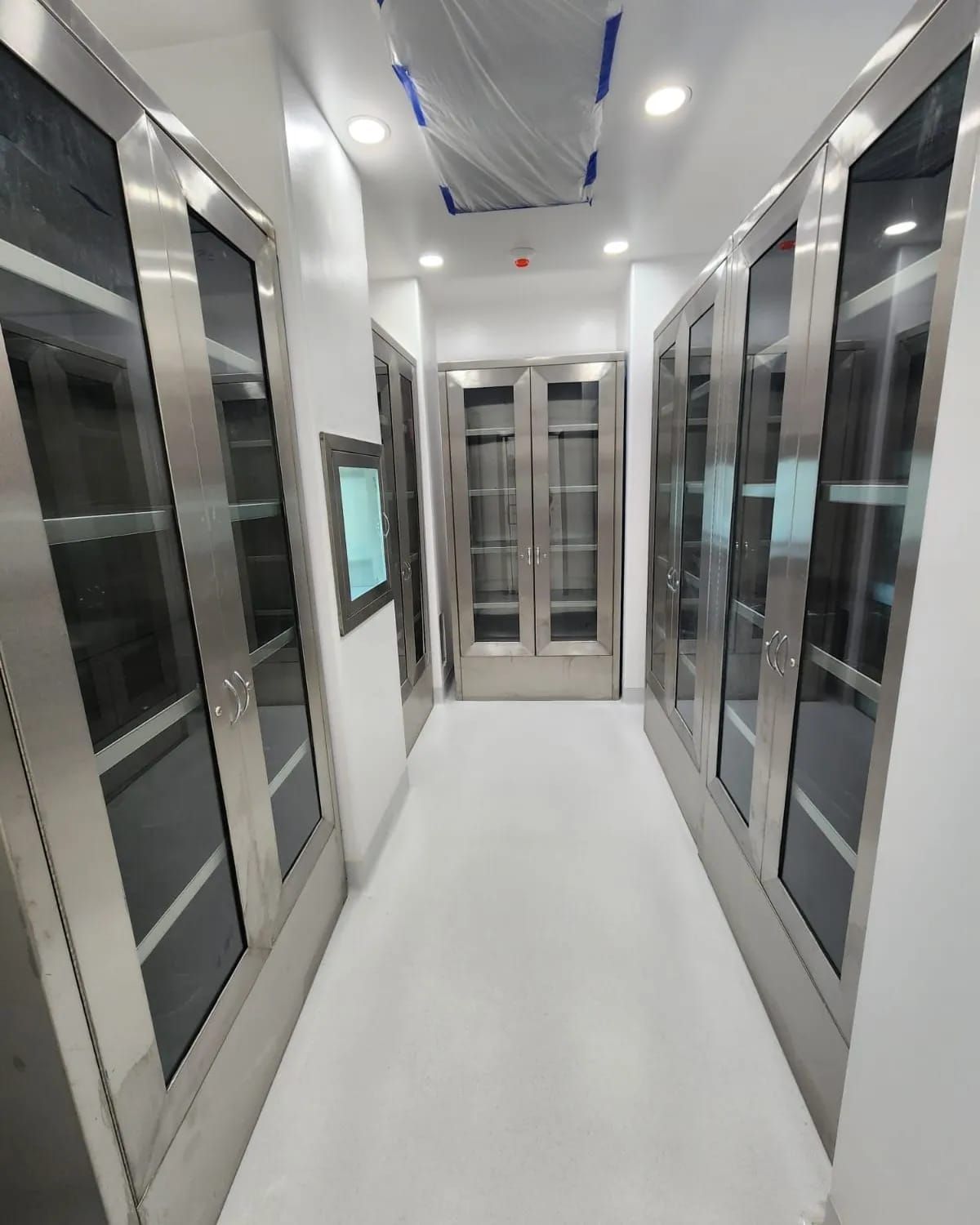 Un largo pasillo con puertas de acero inoxidable y puertas de cristal.