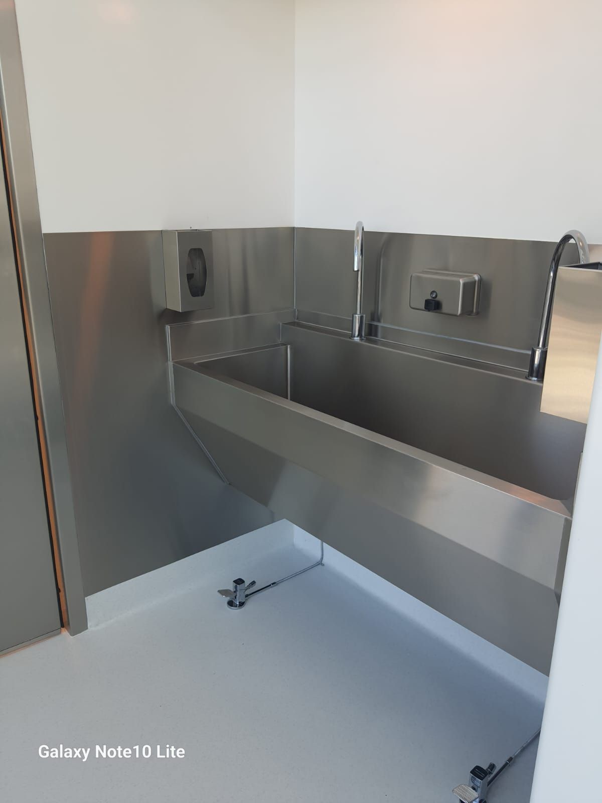 Un lavabo de acero inoxidable en un baño con un galaxy note 10 lite