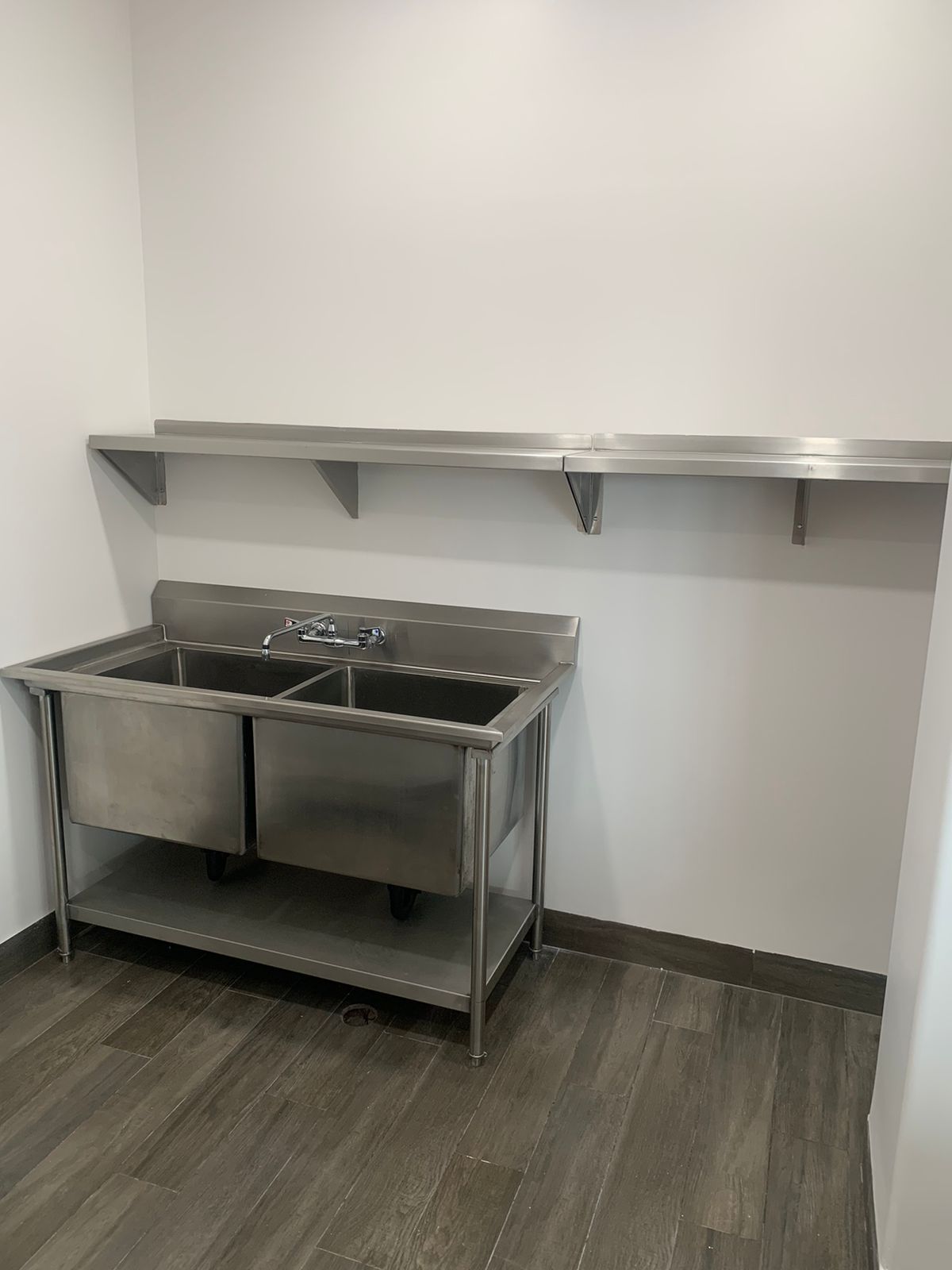 Una cocina con dos fregaderos de acero inoxidable y una estantería.