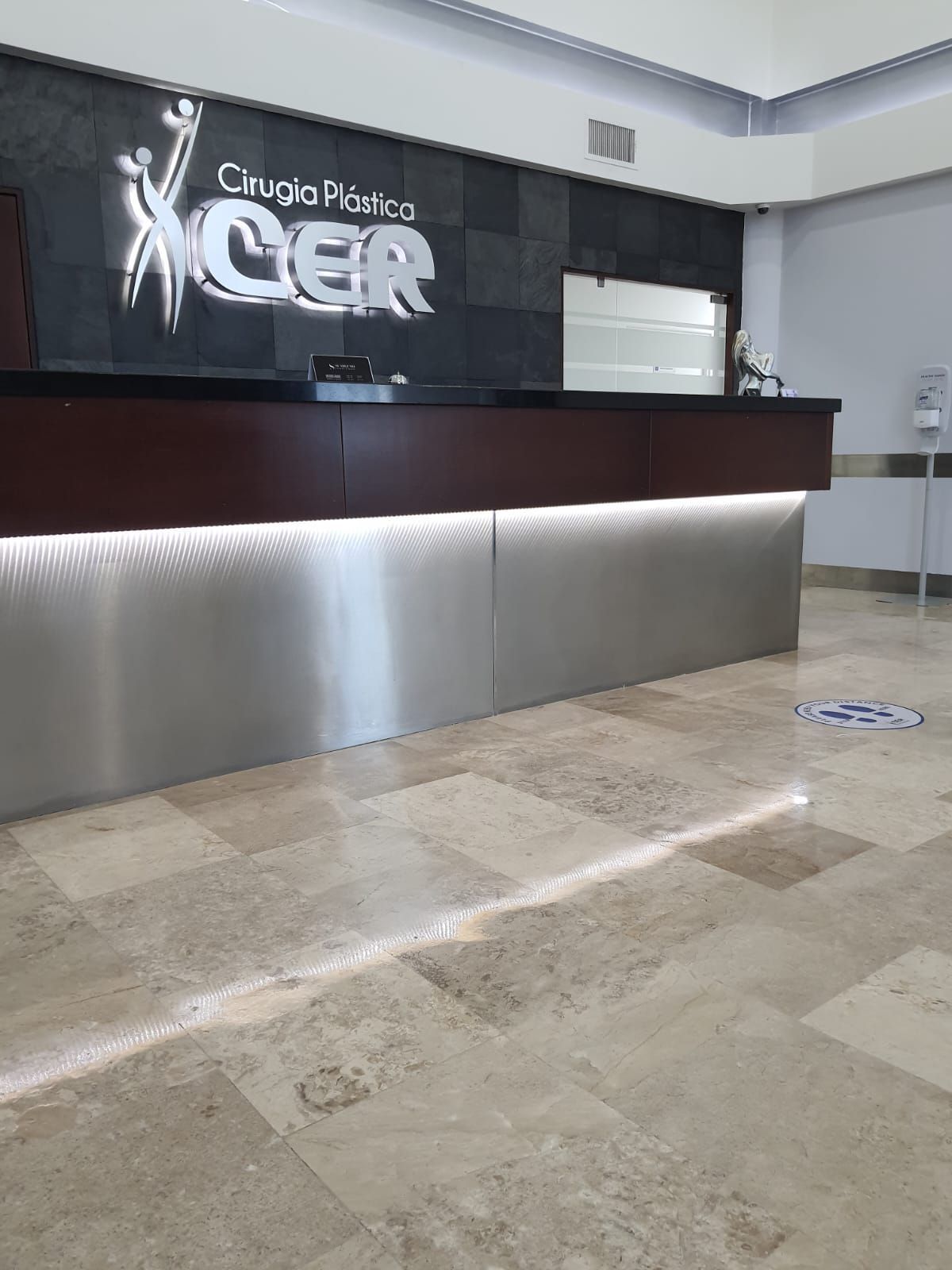 Un mostrador de recepción de acero inoxidable en un hospital con un cartel en la pared.