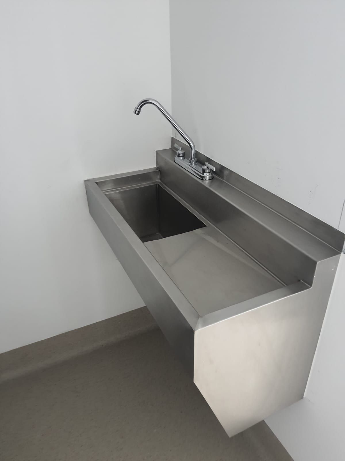 Un lavabo de acero inoxidable con grifo en un baño.