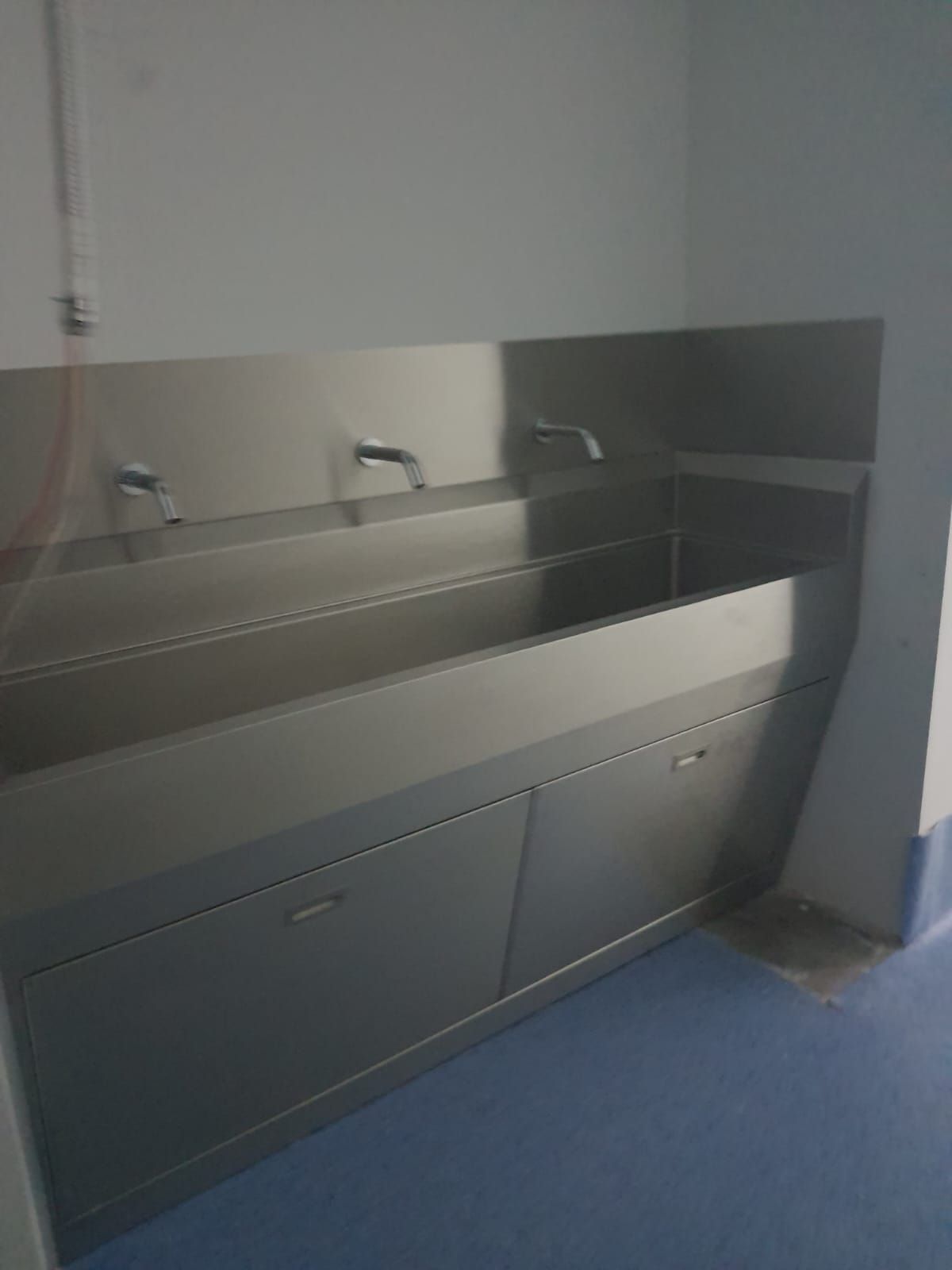 Un fregadero de acero inoxidable con tres grifos en una habitación.