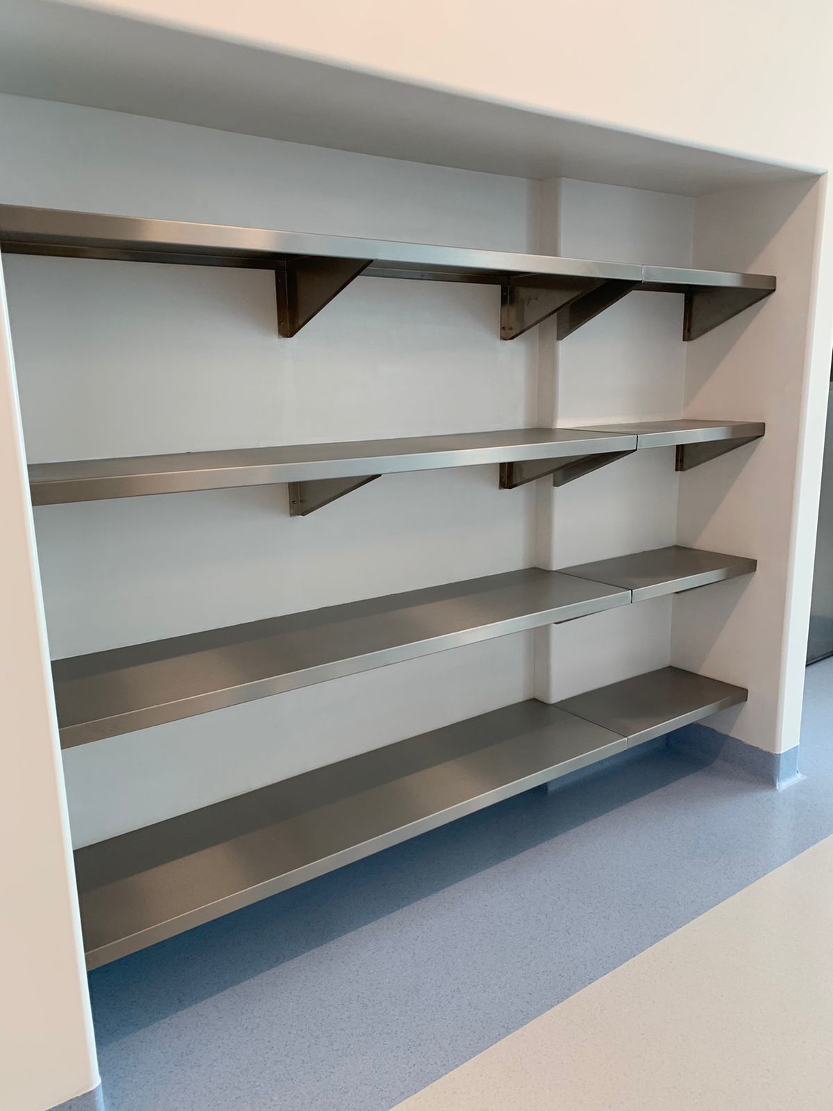 Una hilera de estantes de acero inoxidable contra una pared blanca de una habitación.