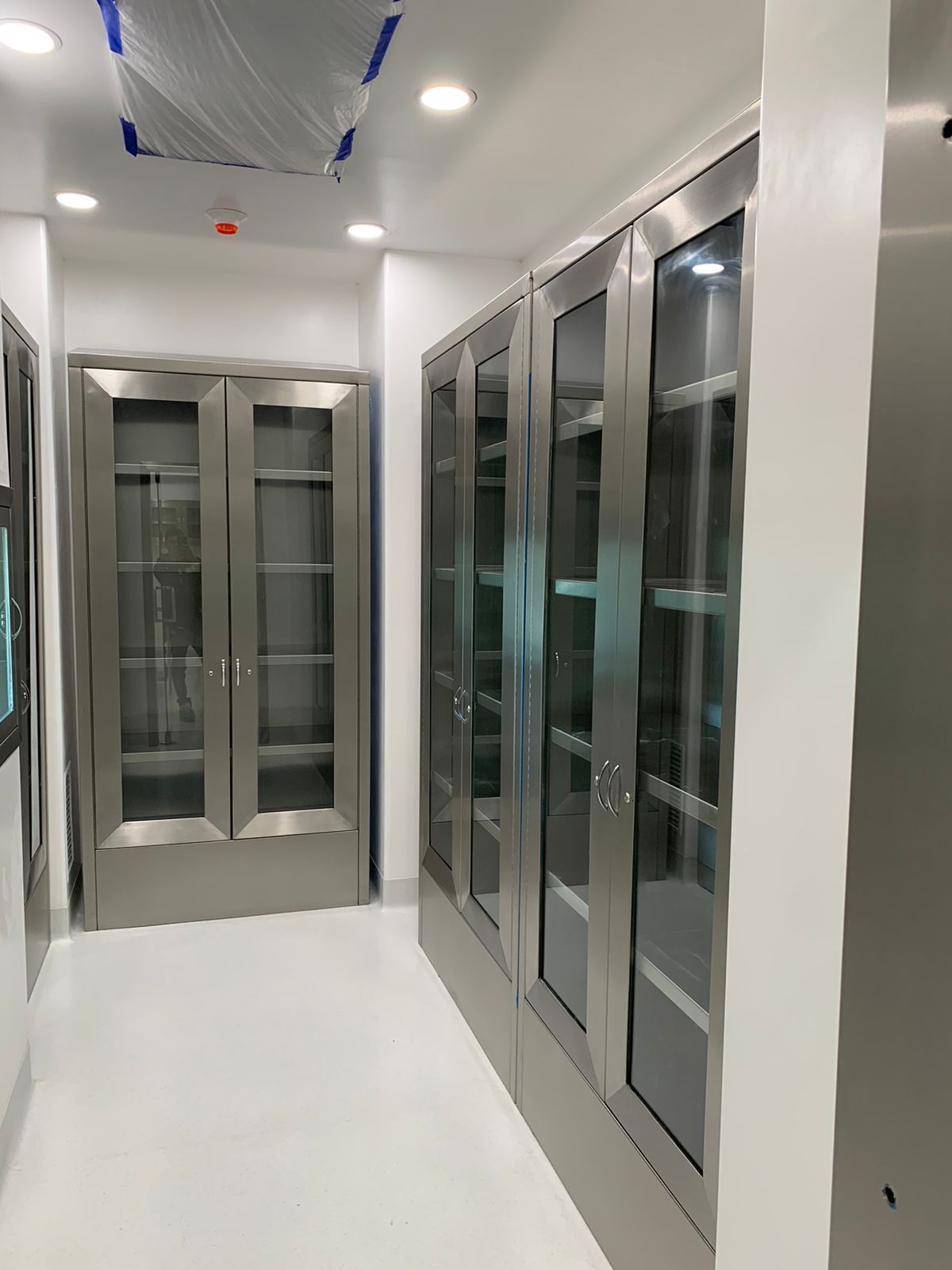 Un pasillo con armarios de acero inoxidable y puertas de cristal.