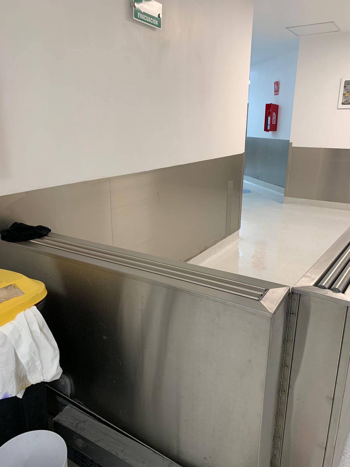 Una pared de acero inoxidable en un pasillo con un extintor de incendios en la pared.