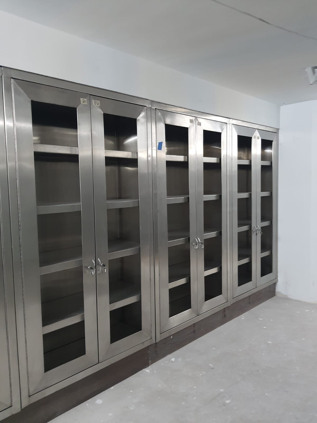 Una fila de armarios de acero inoxidable con puertas de cristal en una habitación.