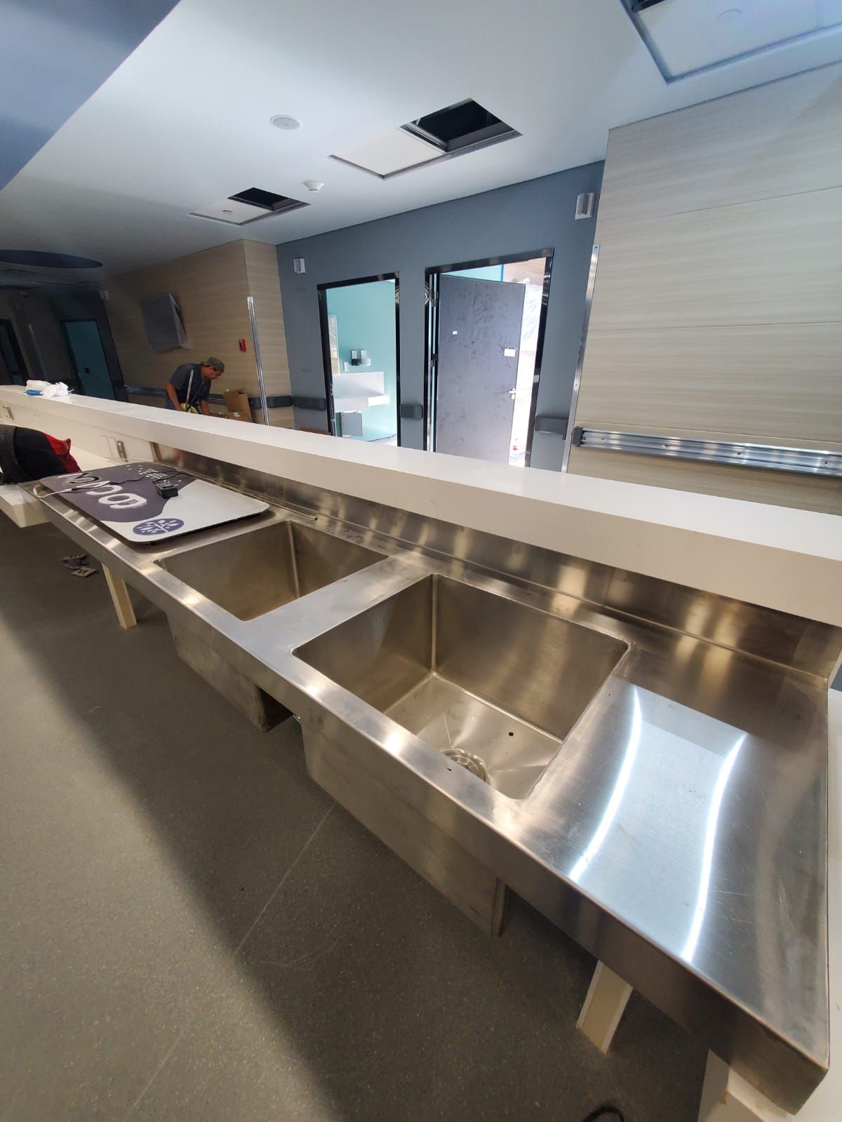 Una larga fila de fregaderos de acero inoxidable en una cocina.