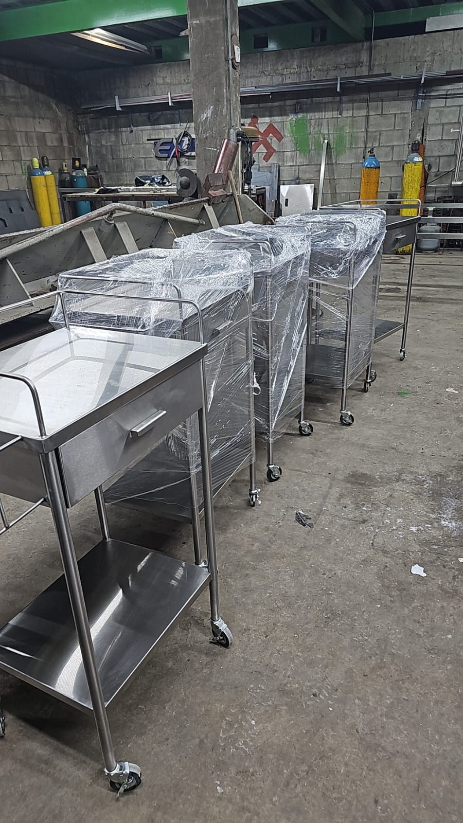 En un almacén hay una fila de carros de acero inoxidable alineados.
