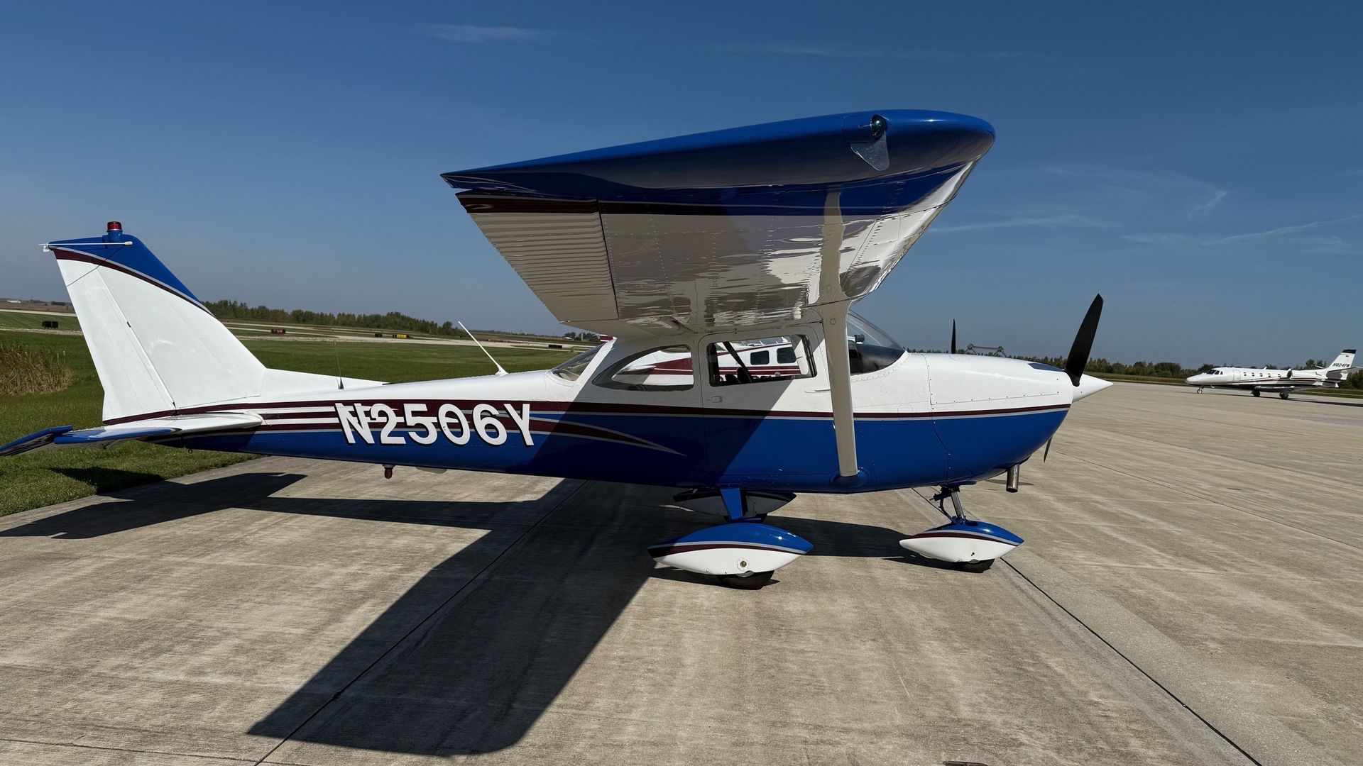 A small red and white plane is parked in front of a building