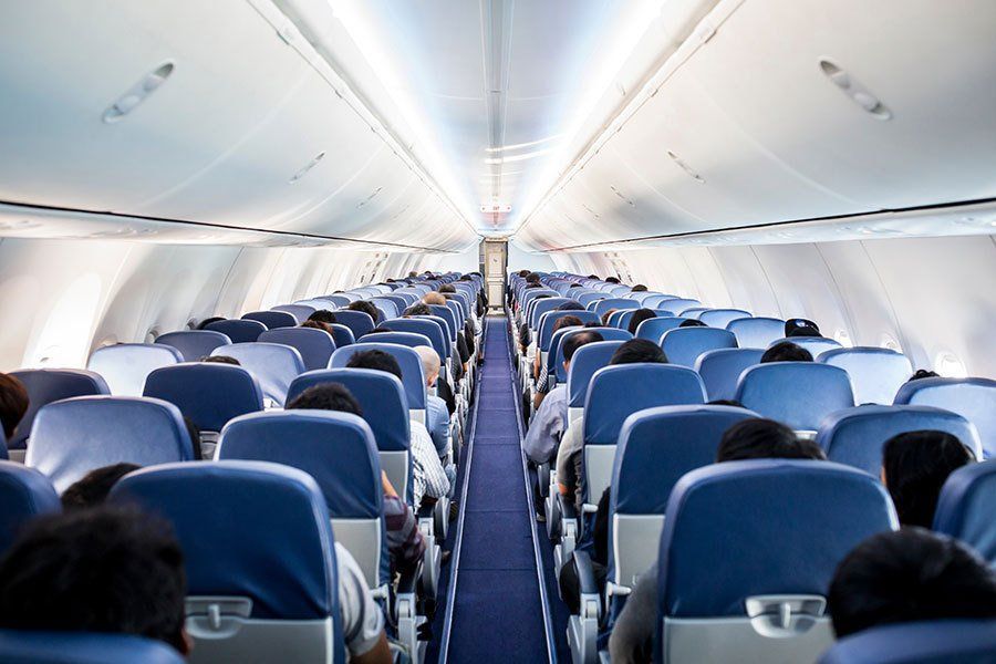 The inside of an airplane filled with people sitting in blue seats.