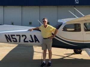 A man in a yellow shirt is standing next to a small plane.