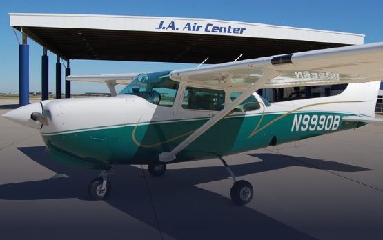 A green and white plane with n99908 on the side is parked in front of the j.a. air center