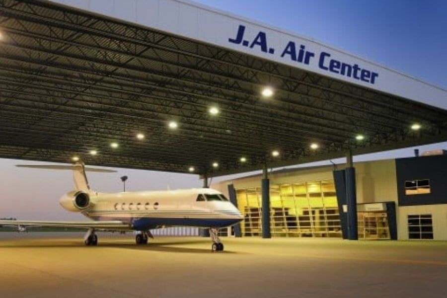 An airplane is parked in front of a building that says j.a. air center