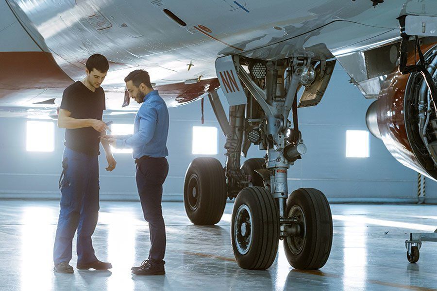 Two men are working on an airplane in a hangar.