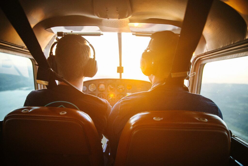 Two pilots are sitting in the cockpit of a small plane.