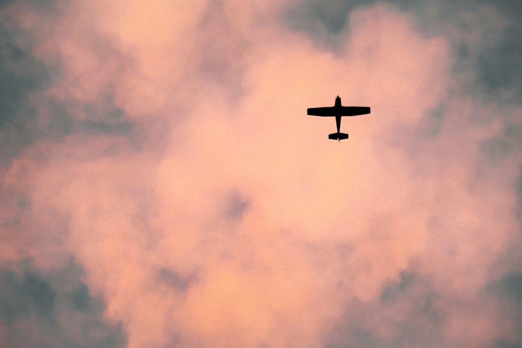 A small plane is flying through a cloudy sky at sunset.